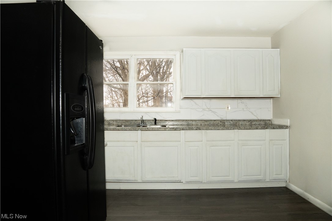 32 Lee Road Painesville, OH 44077 - Photo 4 of 12 Kitchen featuring black refrigerator with ice dispenser, white cabinets, tasteful backsplash, sink, and dark hardwood / wood-style floors