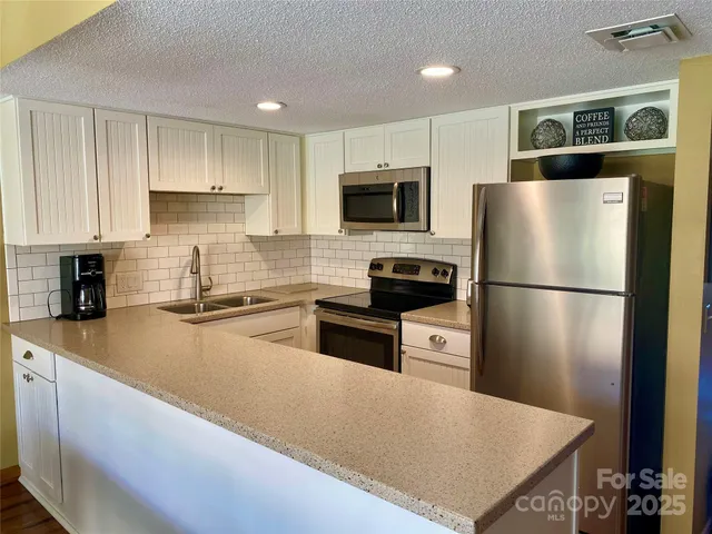 a kitchen with stainless steel appliances granite countertop a refrigerator a stove a sink and a microwave