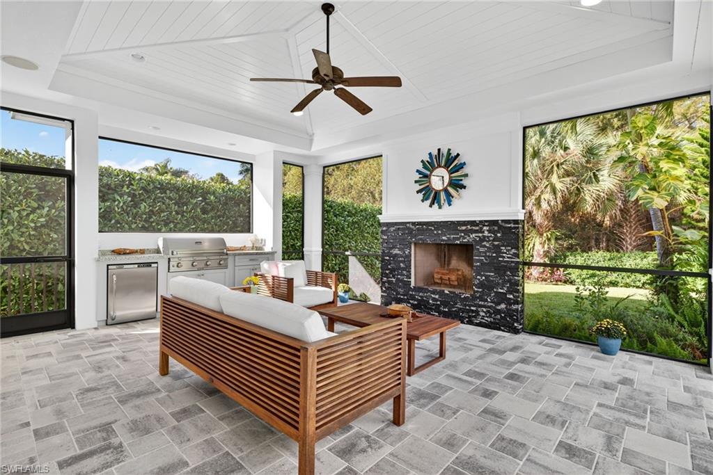 2305 Harrier Run Naples, FL 34105 - Photo 38 of 50 a living room with furniture a fireplace and a floor to ceiling window
