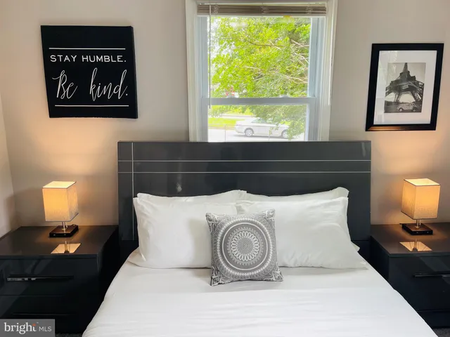 a bedroom with a bed and a lamp on dresser