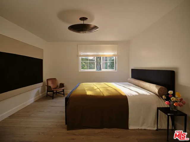 a bedroom with a bed and a flat tv screen on dresser