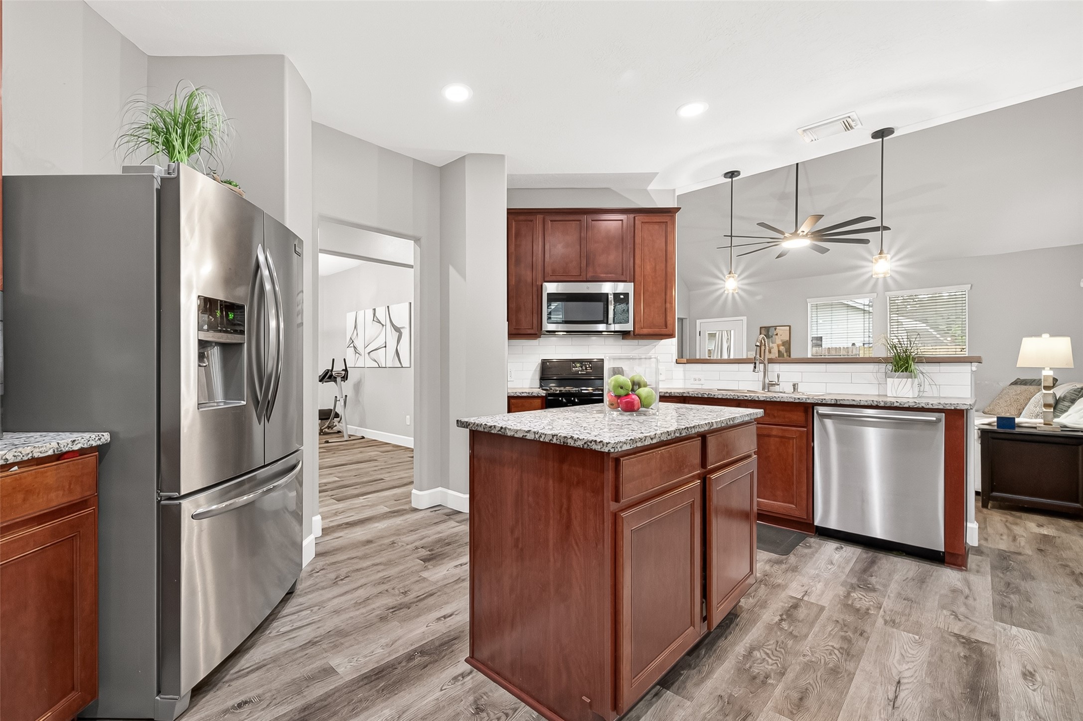 7415 Riven Oaks Court Cypress, TX 77433 - Photo 15 of 42 Another view of the modern kitchen showcases stainless steel appliances, granite countertops, and a spacious center island, all opening seamlessly into the inviting living room for effortless entertaining and everyday living.