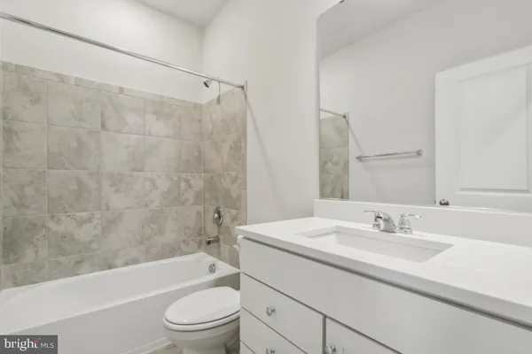 a bathroom with a granite countertop sink a toilet a mirror a bathtub and shower