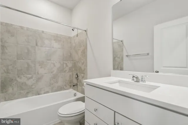 a bathroom with a granite countertop sink a toilet a mirror a bathtub and shower