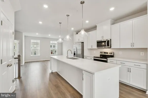 a kitchen with stainless steel appliances a stove a sink a refrigerator a center island and cabinets