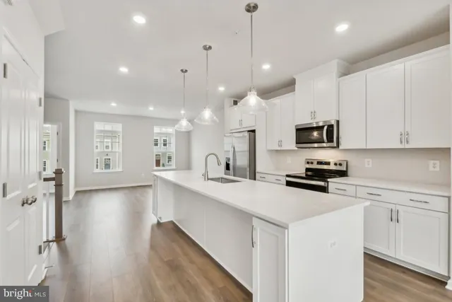 a kitchen with stainless steel appliances a stove a sink a refrigerator a center island and cabinets