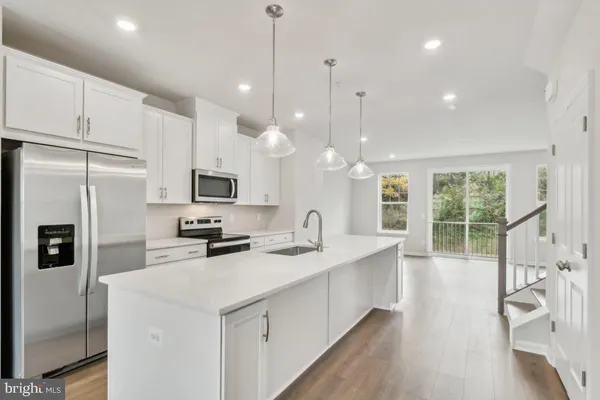 a kitchen with stainless steel appliances kitchen island granite countertop a sink a stove and a refrigerator