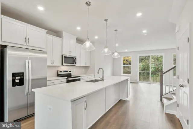 a kitchen with stainless steel appliances kitchen island granite countertop a sink a stove and a refrigerator