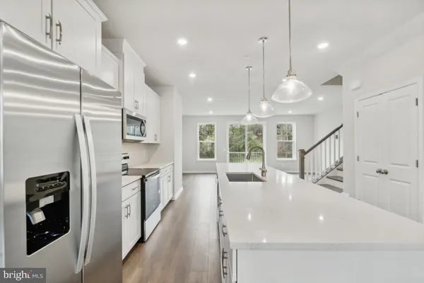 a kitchen with stainless steel appliances a refrigerator a sink dishwasher a oven and a large window with wooden floor