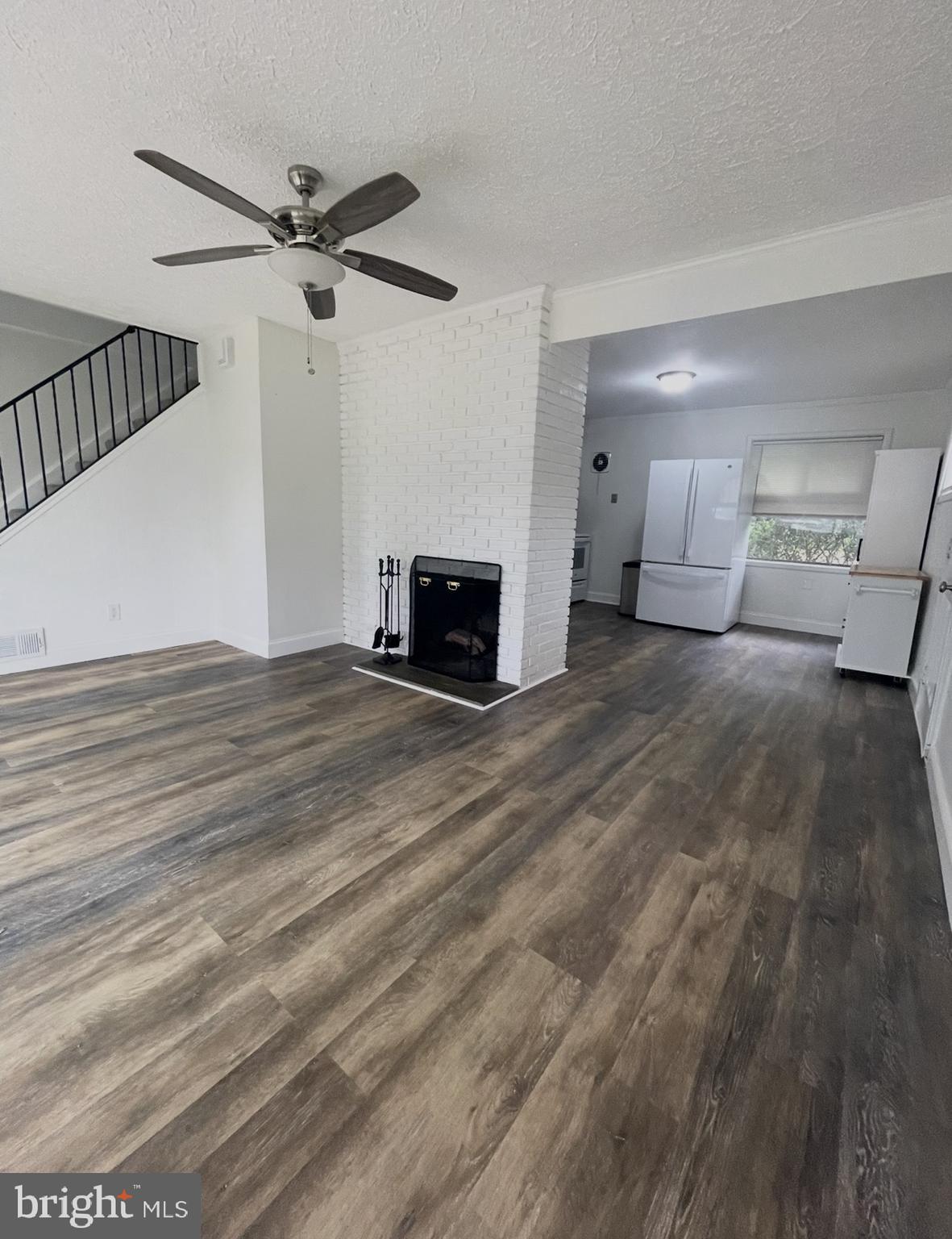 5700 Stillwell Road Rockville, MD 20851 - Photo 5 of 19 a view of a livingroom with a fireplace a ceiling fan and wooden floor