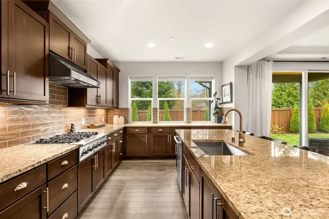 a kitchen that has a lot of cabinets a sink a stove and wooden floor