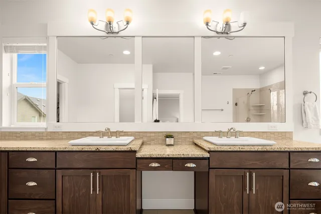 a spacious bathroom with a granite countertop double vanity and mirrors