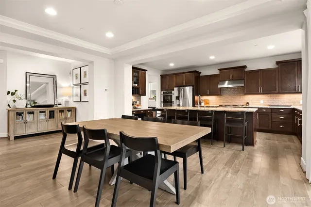 a kitchen with stainless steel appliances kitchen island granite countertop a table chairs sink and cabinets