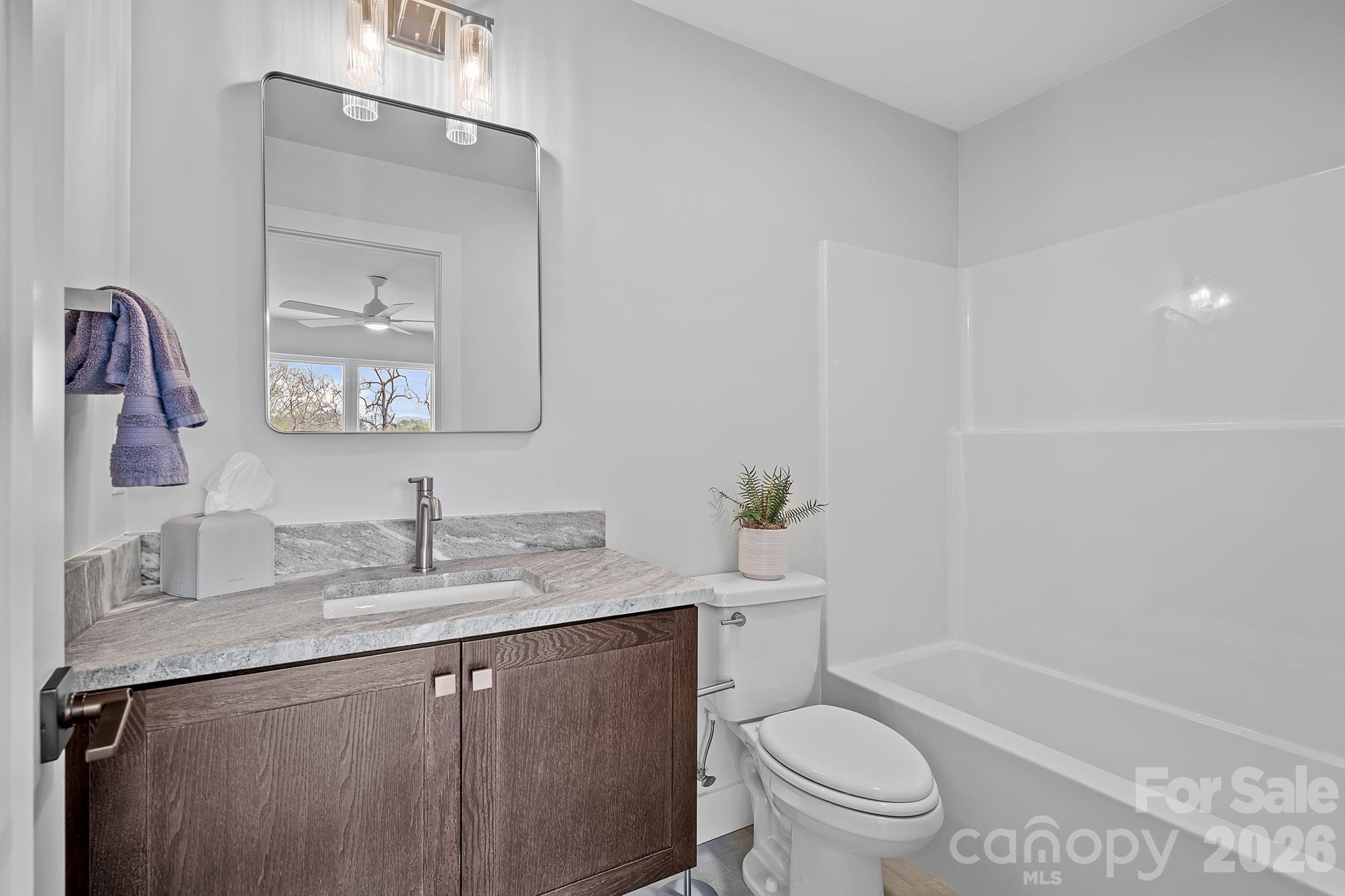 9 Gudger Road Asheville, NC 28715 - Photo 35 of 43 a bathroom with a granite countertop sink a toilet and a mirror