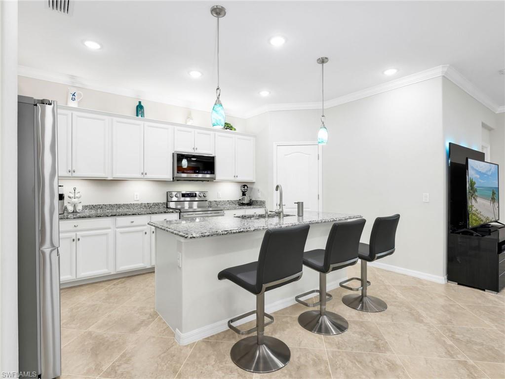 4383 Bismark Way Naples, FL 34119 - Photo 6 of 49 Kitchen with Island, White Shaker Cabinetry, Sparkling New Stainless Steel LG Appliances, Under & Above Counter Lighting, Crown Molding, & Pendant Lighting