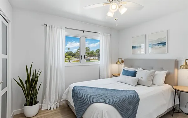 a bedroom with a large bed and a potted plant