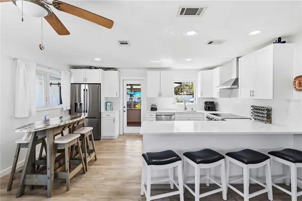 a large white kitchen with lots of counter space and stainless steel appliances