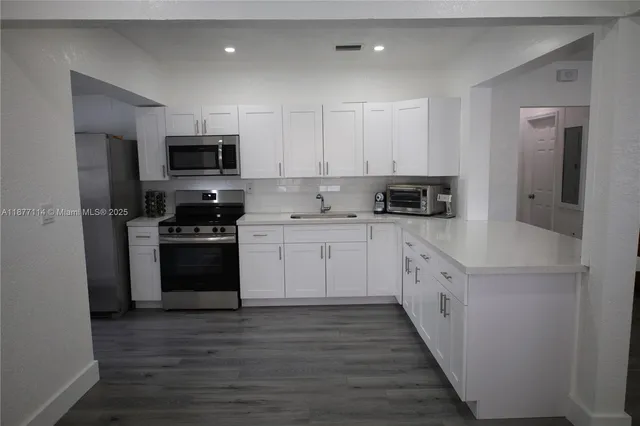 a kitchen with granite countertop a sink a stove a refrigerator and cabinets