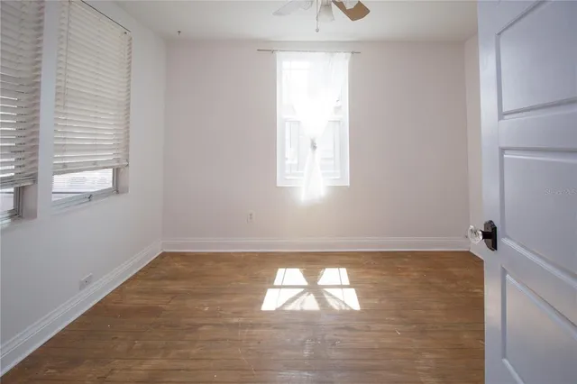 an empty room with windows and fan