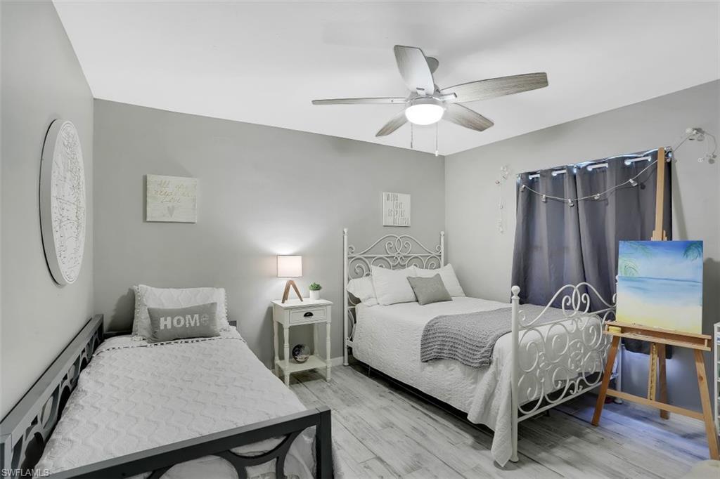 7359 Stonegate Drive Naples, FL 34109 - Photo 21 of 33 a bedroom with a bed wooden floor and table