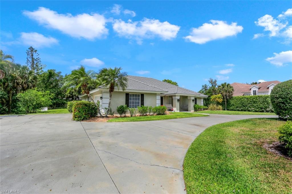 7359 Stonegate Drive Naples, FL 34109 - Photo 32 of 33 a front view of a house with a yard and trees