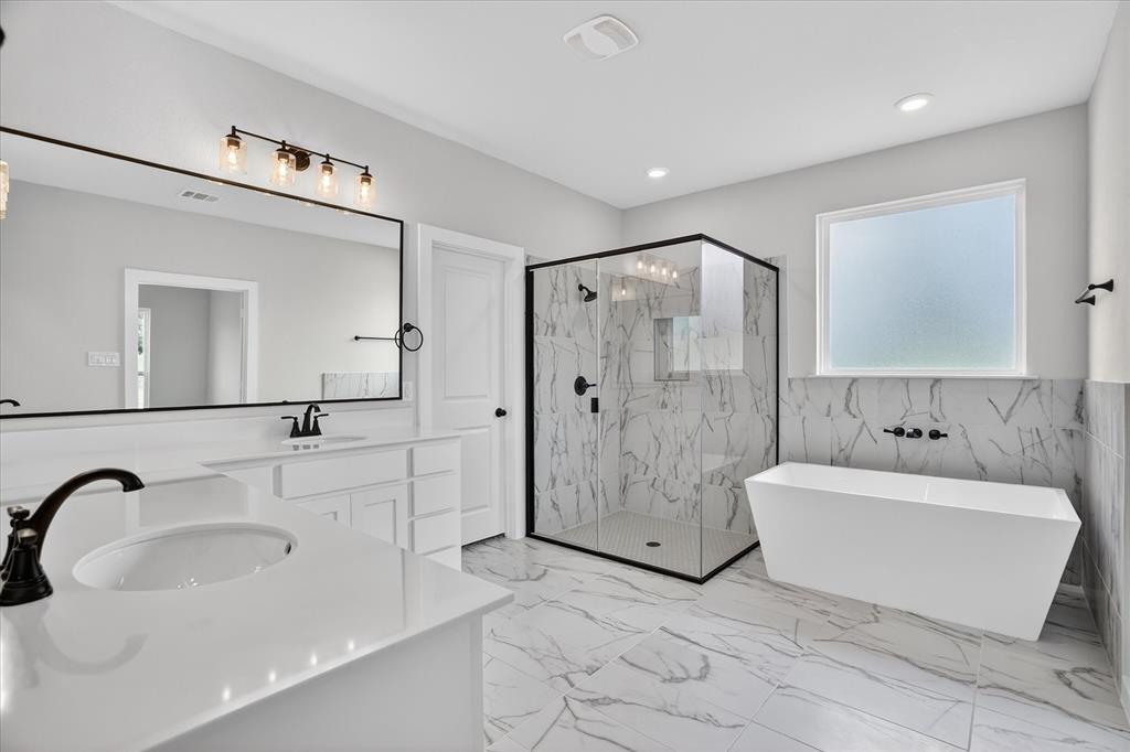 317 Skeen Peak Springtown, TX 76082 - Photo 23 of 31 Spacious bathroom featuring a freestanding soaking tub, a frameless glass shower enclosure, and dual vanities with white countertops