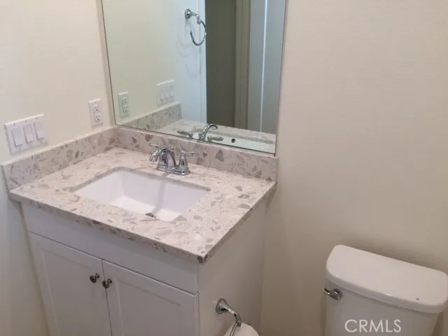 a bathroom with a granite countertop toilet sink and mirror