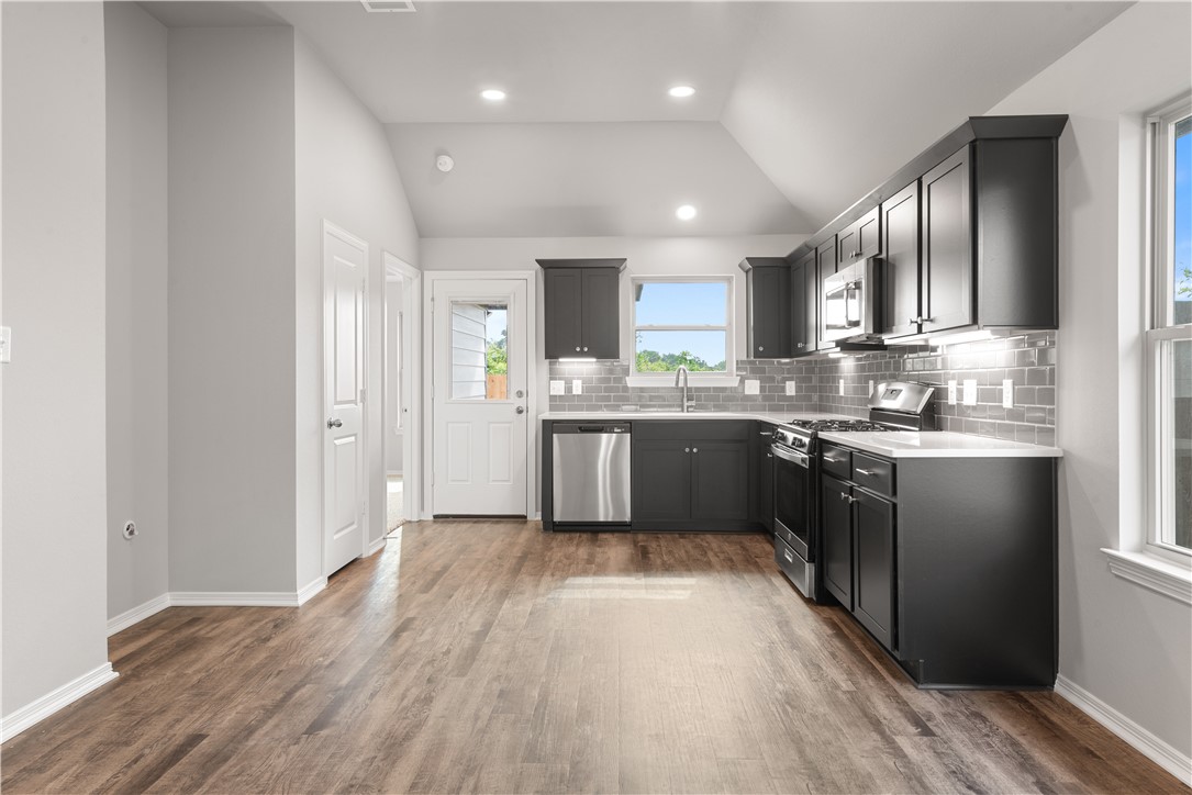 2869 Messenger Way Bryan, TX 77803 - Photo 7 of 23 a kitchen with stainless steel appliances granite countertop wooden cabinets a refrigerator a sink a stove and a wooden floors