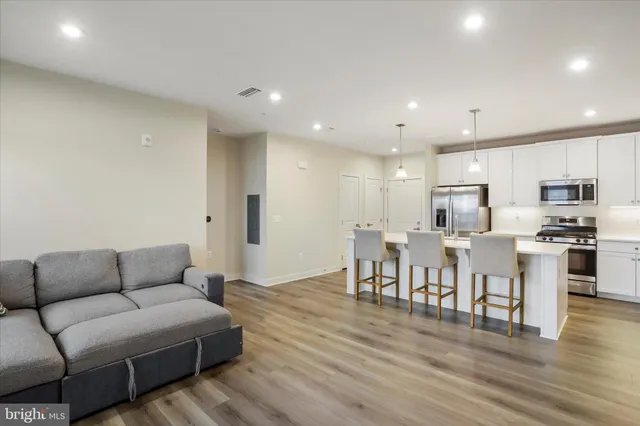 a living room kitchen with furniture and a wooden floor