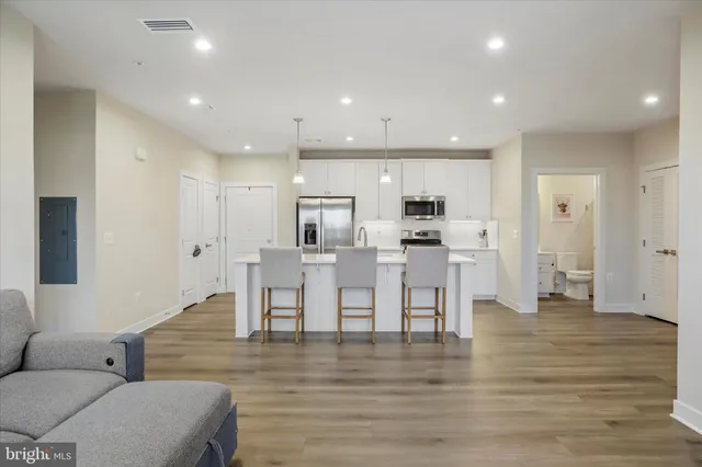 a living room with furniture wooden floor and a kitchen view