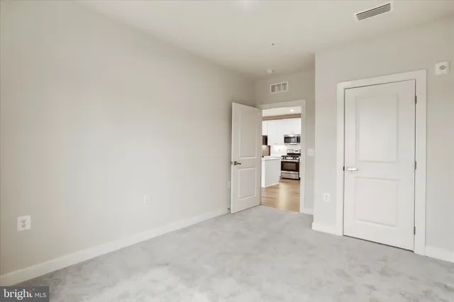 a view of a kitchen with refrigerator and white wall