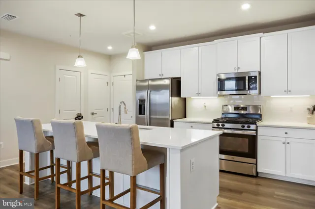 a kitchen with stainless steel appliances granite countertop a stove a refrigerator a kitchen island a dining table and chairs