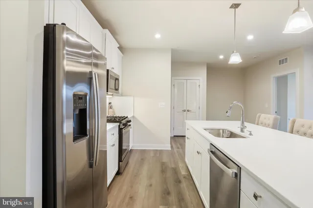 a kitchen with a sink a refrigerator and wooden floor