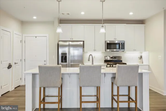 a kitchen with kitchen island granite countertop a refrigerator and microwave