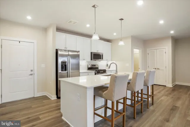 a kitchen with stainless steel appliances a dining table chairs refrigerator sink and microwave