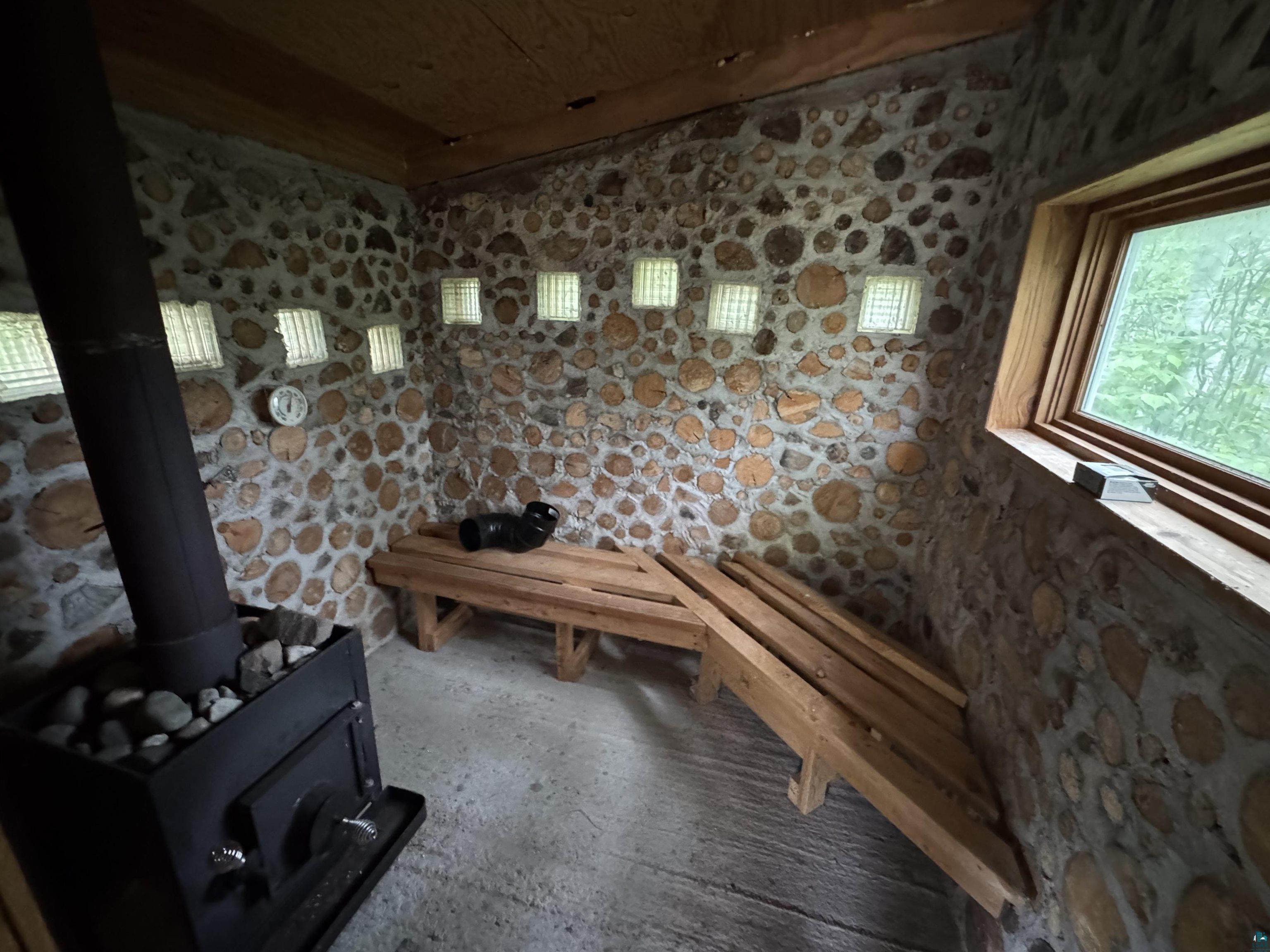 1745 Becks Road Maple, WI 54854 - Photo 41 of 46 Cordoned wood and stone wall finish with glass block accents, wood-frame window, and a built-in wood stove