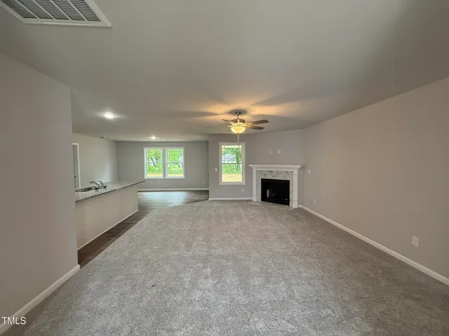 a view of an empty room with a fireplace and a window