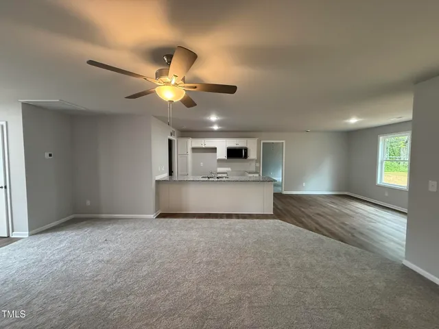 a view of an empty room and kitchen view