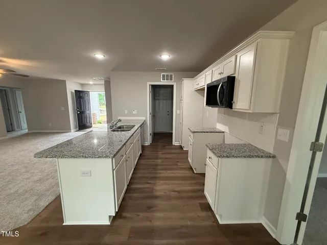 a large bathroom with a granite countertop sink a large mirror and a refrigerator