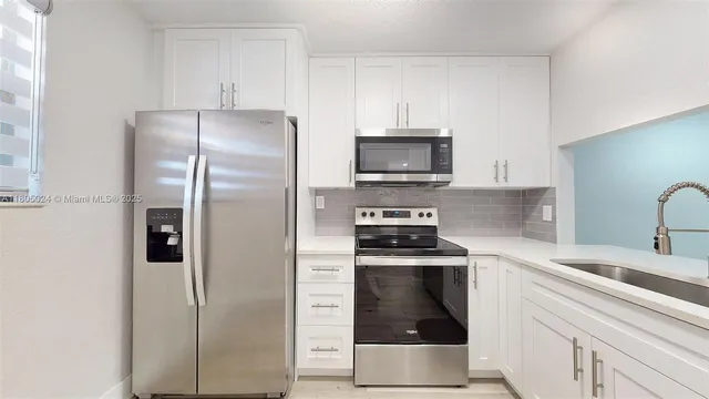 a kitchen with cabinets stainless steel appliances and wooden floor