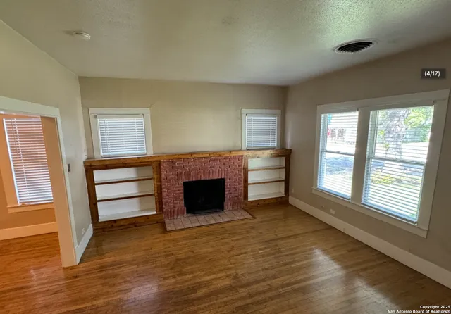 a view of an empty room with a fireplace and a window