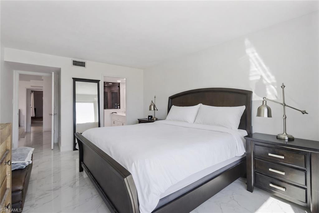 452 Bristle Cone Lane, Unit 27 Naples, FL 34113 - Photo 9 of 16 Bedroom featuring light marble finish floors and ensuite bathroom