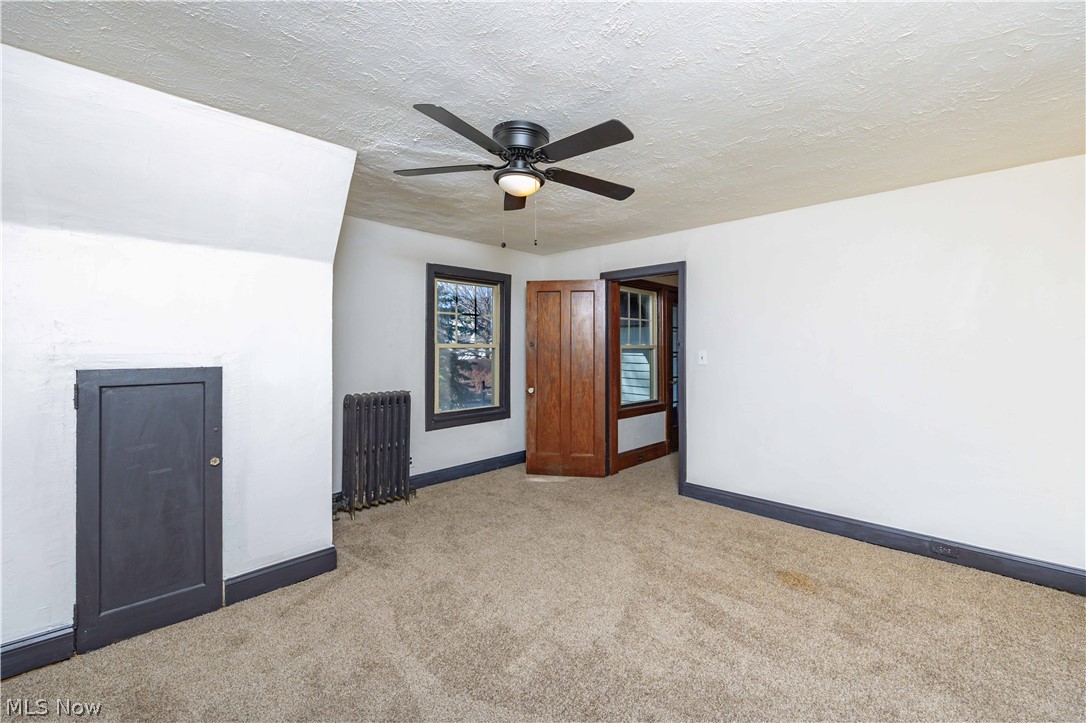 3254 Redwood Road Cleveland Heights, OH 44118 - Photo 38 of 49 Carpeted empty room with radiator heating unit, ceiling fan, and a textured ceiling