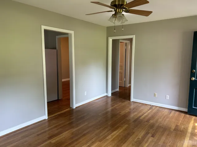 an empty room with wooden floor closet and windows