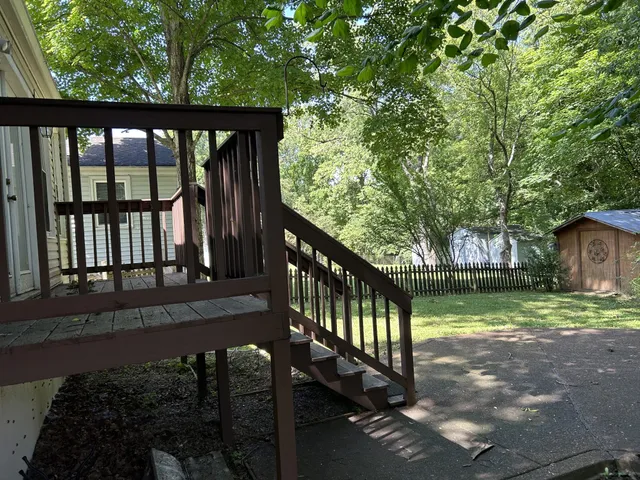 a view of a wooden deck and a yard with large tree