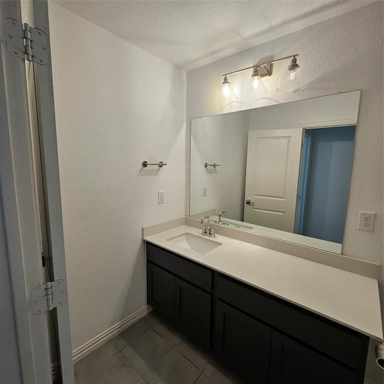 2309 Jack Rabbit Way Northlake, TX 76247 - Photo 15 of 28 Bathroom featuring a spacious vanity with dark cabinetry, light-toned countertop, and an integrated sink