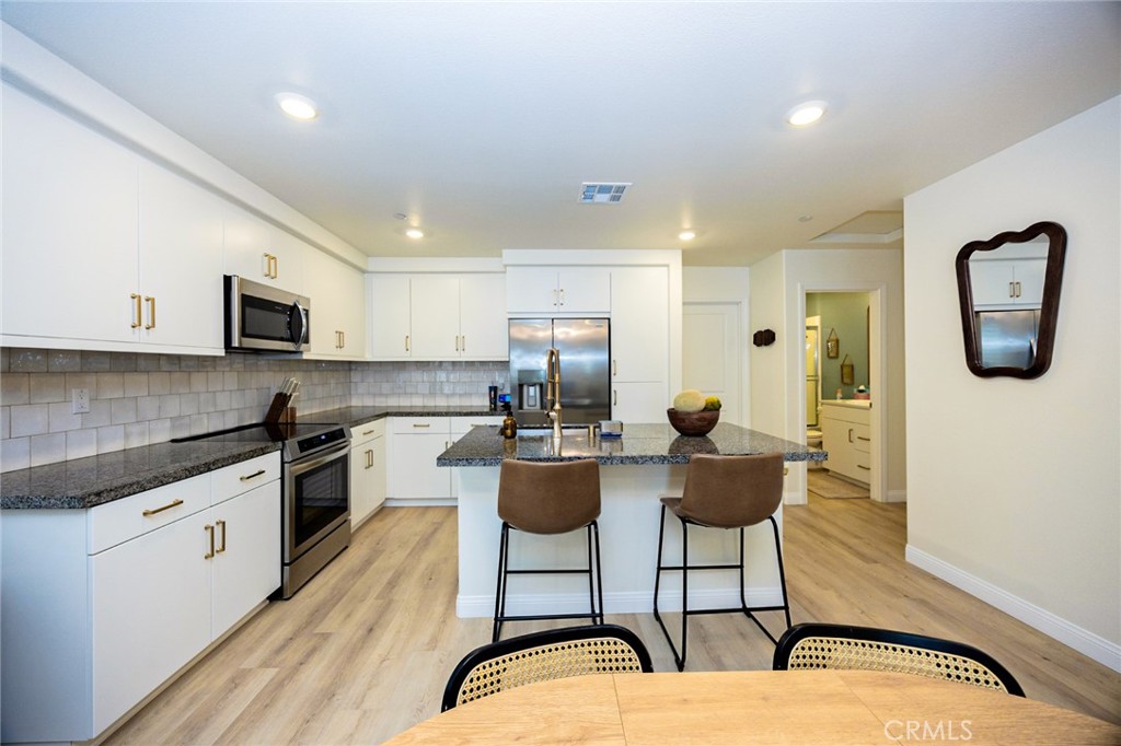 19245 Sequoia Grv Street Riverside, CA 92507 - Photo 9 of 25 a kitchen with stainless steel appliances granite countertop a stove top oven a sink a dining table and chairs with wooden floor