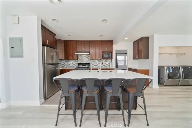 a kitchen with stainless steel appliances granite countertop a dining table chairs refrigerator and sink