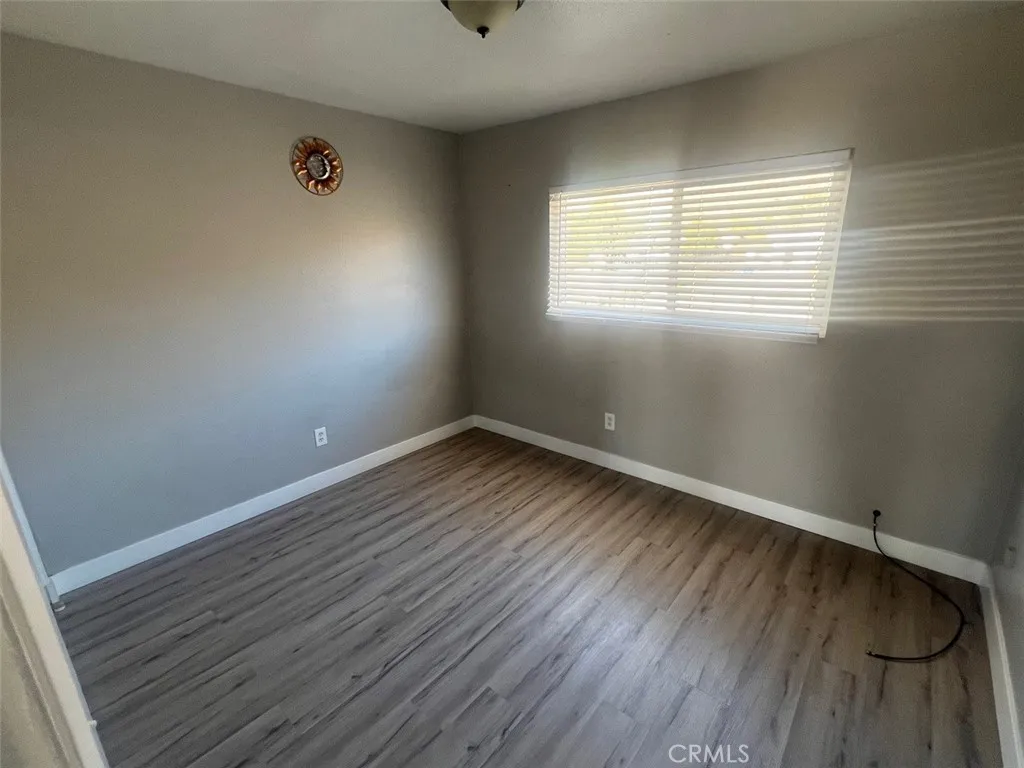1064 West 48th Street San Bernardino, CA 92415 - Photo 7 of 12 an empty room with wooden floor and windows