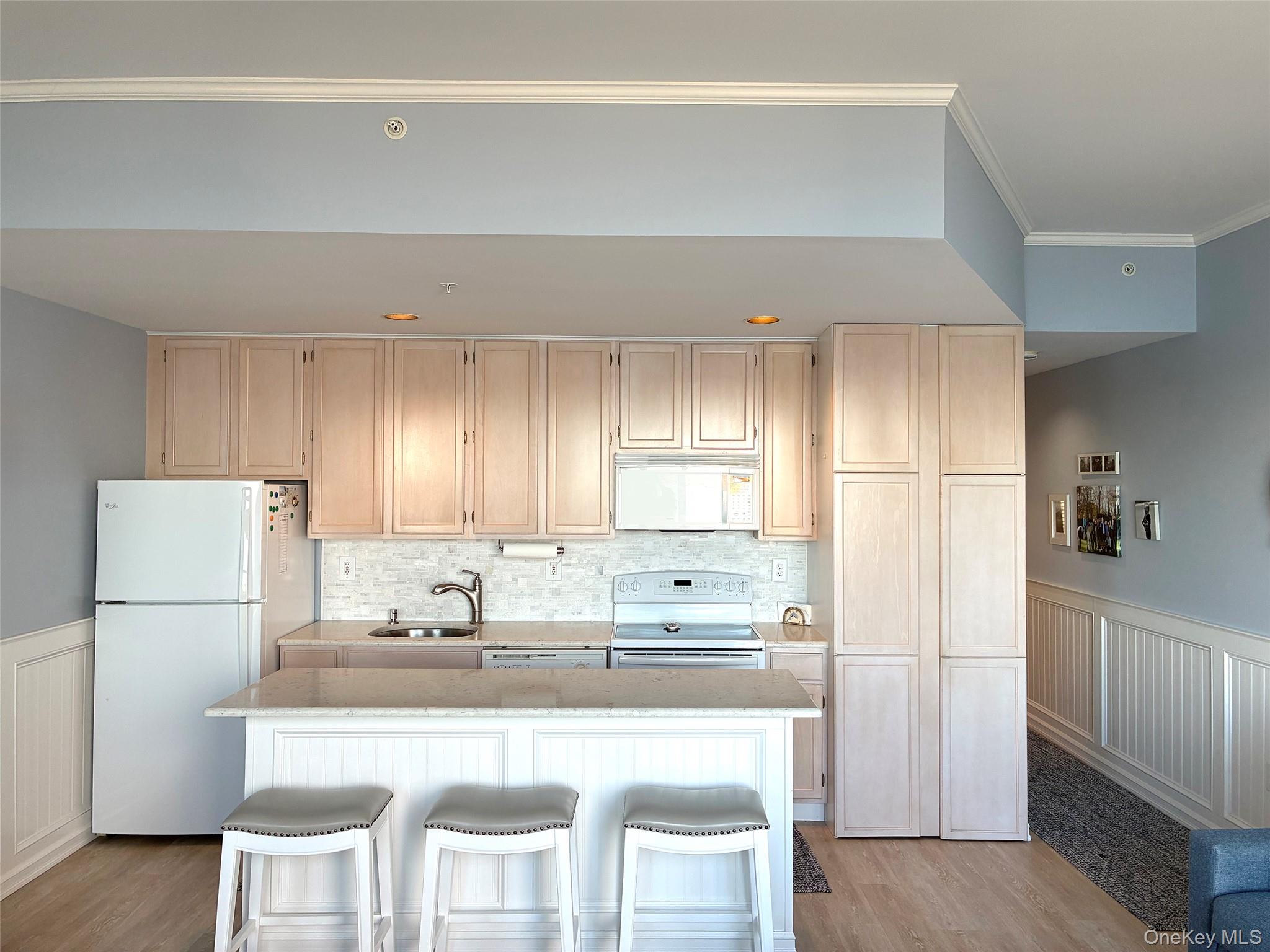 250 Dune Road, Unit 120 Westhampton Beach, NY 11978 - Photo 5 of 11 a kitchen with stainless steel appliances granite countertop a refrigerator a stove a sink and white cabinets with wooden floor